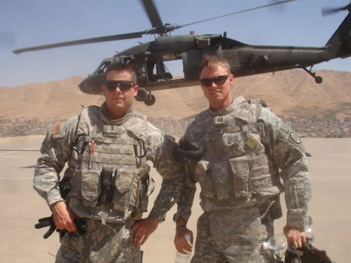 Major Mike Perry and a fellow soldier near a military helicopter during Operation Iraqi Freedom